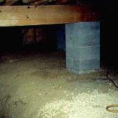 This picture shows a dirt crawl space under a building. Avanty Construction spreads out the plastic sheeting to fit the area and then seals it to the walls to create an air tight space.